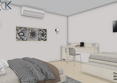 Chambre d'hôtel, sur la gauche un lit avec couverture gris/ marron clair/ beige. En face du lit un petit canapé gris au dessus et beige. Au dessus du canapé et en face du lit, télévision est visible. A gauche du canapé un petit bureau de couleur beige ou bis clair. Sur le mur a gauche du lit, trois tableaux sont visible avec des appliques lumineuse de chaque côtés. Une climatisation est au dessus des tableaux